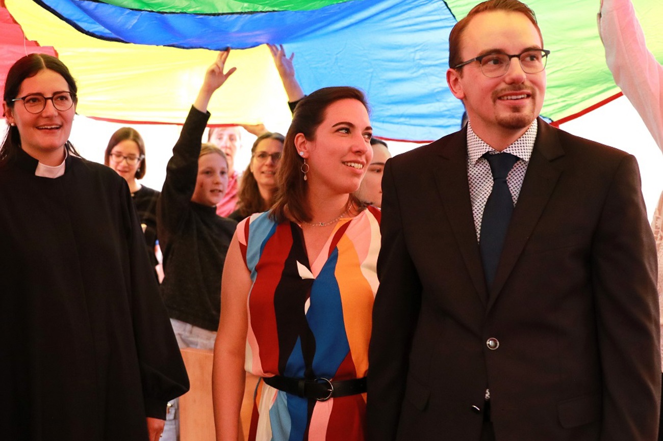 Aylin Weets (links) und Micha Rippert (rechts) standen zum Schluss des Ordinationsgottesdienstes unter einem farbigen Fallschirm. (Bild: Claudia Koch)