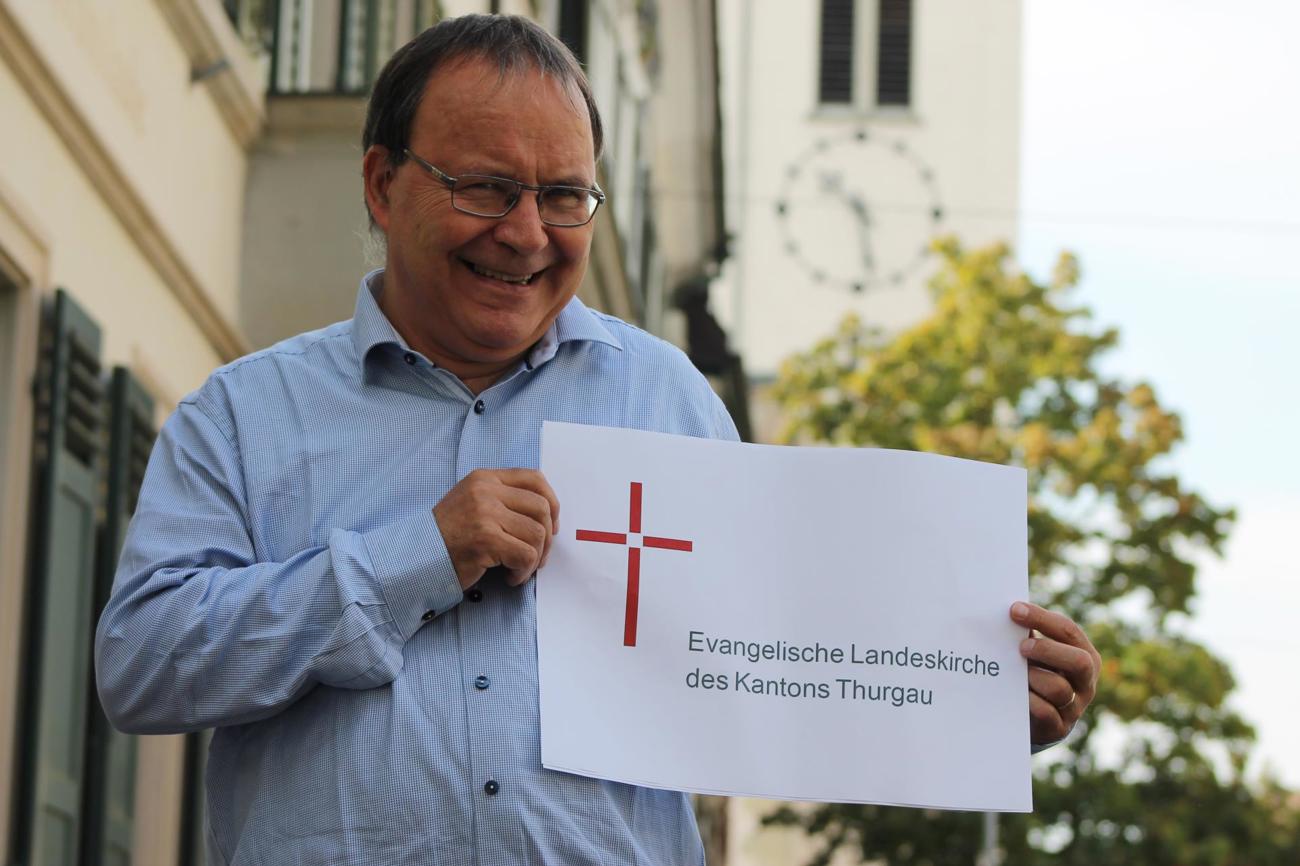 Kirchenratsaktuar Ernst Ritzi präsentiert das neue Logo «Kreuz im Licht».